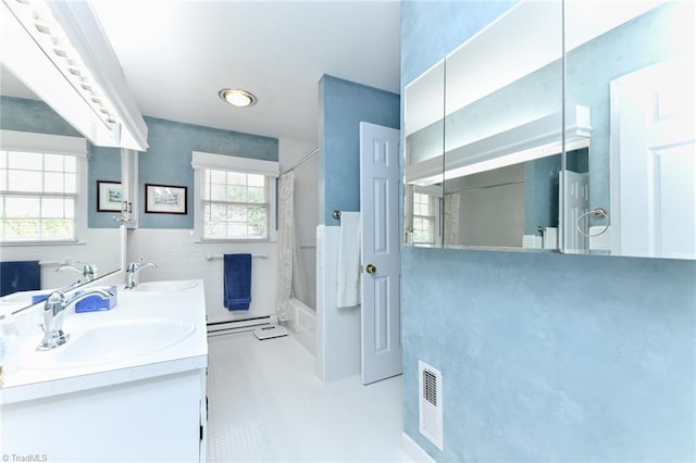 full bath with shower / bath combo, tile walls, a sink, and a baseboard heating unit