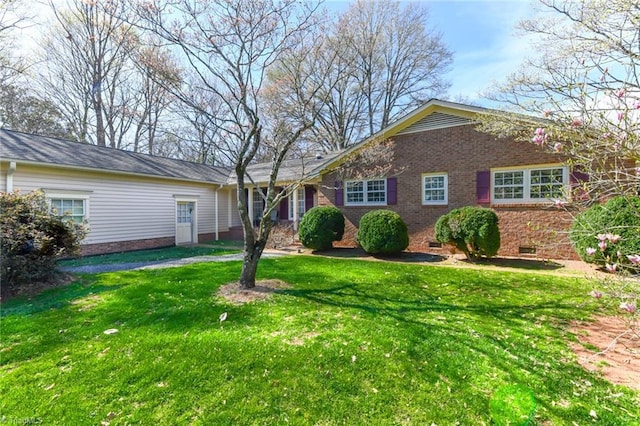 view of front of home with brick siding, crawl space, and a front yard