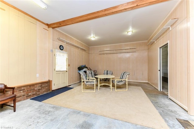 dining room with unfinished concrete flooring, wood walls, and beam ceiling