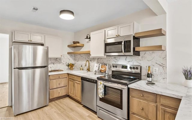 kitchen with tasteful backsplash, appliances with stainless steel finishes, sink, and white cabinets