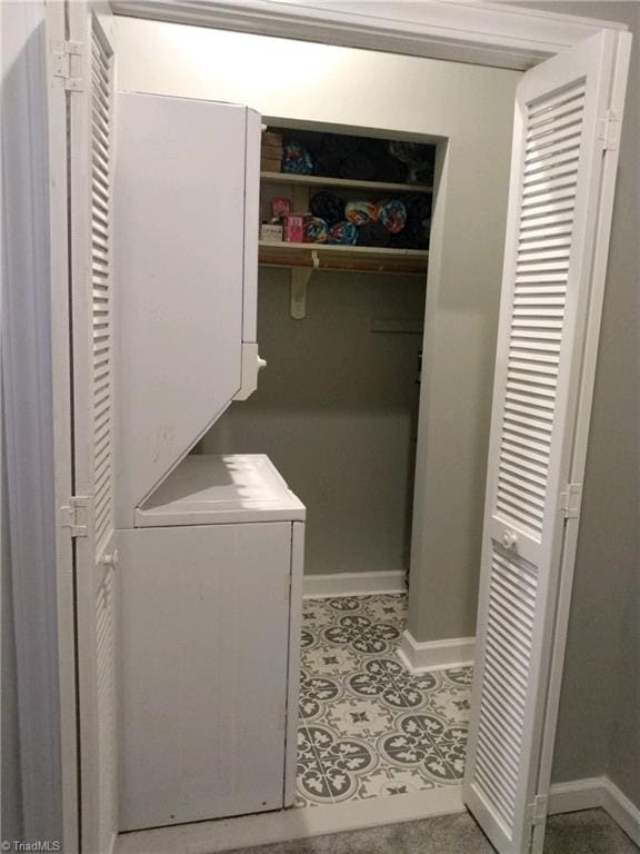 laundry room featuring stacked washer / drying machine and tile patterned flooring