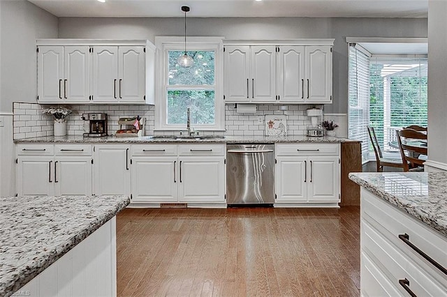 kitchen featuring plenty of natural light, white cabinetry, hardwood / wood-style floors, and stainless steel dishwasher