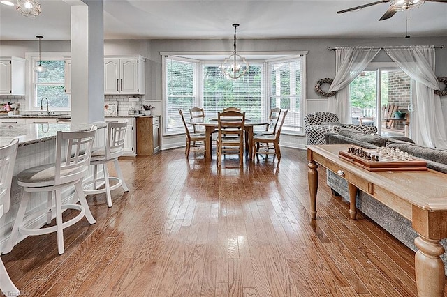 dining space featuring hardwood / wood-style flooring, ceiling fan with notable chandelier, and sink