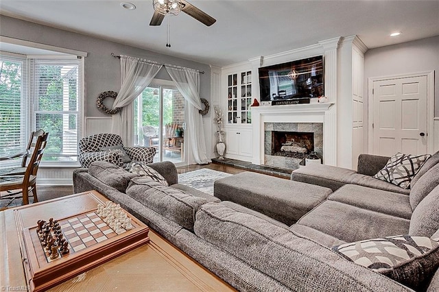 living room with wood-type flooring, a tiled fireplace, a wealth of natural light, and ceiling fan