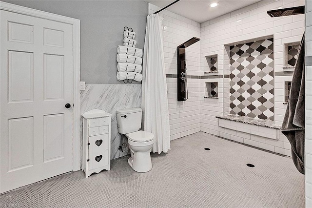 bathroom with toilet, a shower with curtain, and tile walls