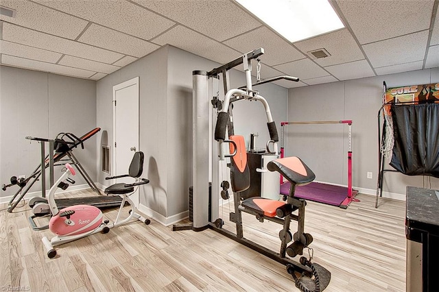 exercise area with light hardwood / wood-style floors and a drop ceiling