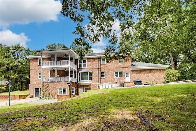 rear view of property featuring a balcony, ceiling fan, and a lawn