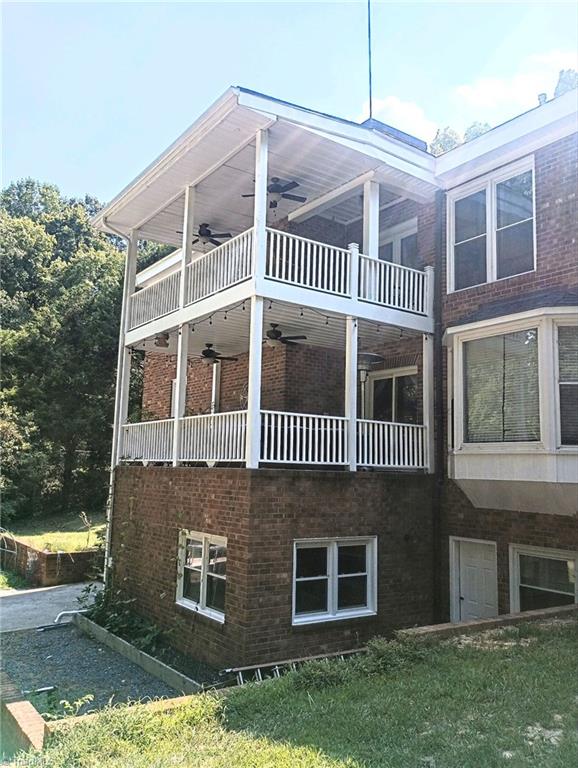 view of side of home with a balcony, ceiling fan, and a lawn