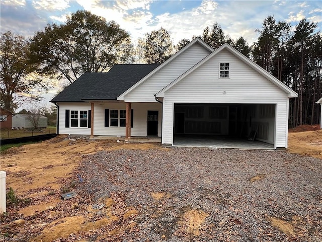 view of front of house with an attached garage, a shingled roof, and gravel driveway