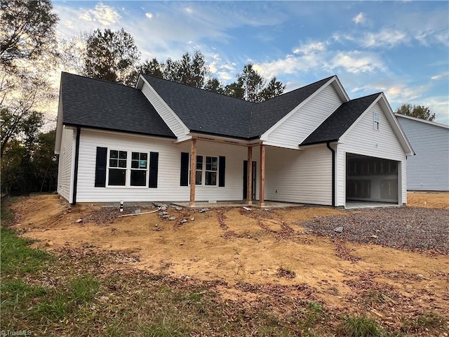 view of front of property with a shingled roof, a garage, and dirt driveway