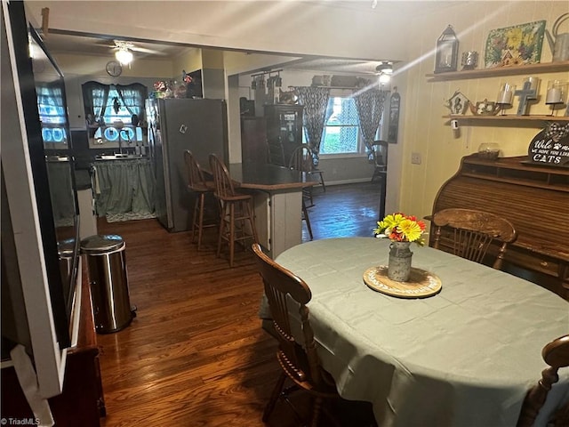 dining room with ceiling fan, dark wood-type flooring, and bar area