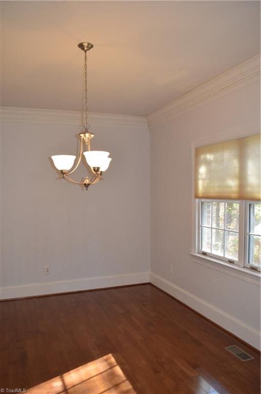 empty room with dark hardwood / wood-style flooring, a chandelier, and crown molding