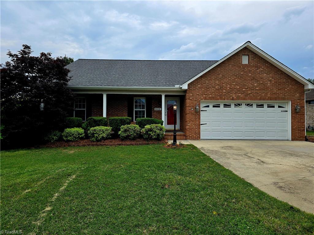 6058 Weant Rd, Archdale, NC 27263 - view of front of house with concrete driveway, an attached garage, brick siding, a front yard, and a shingled roof