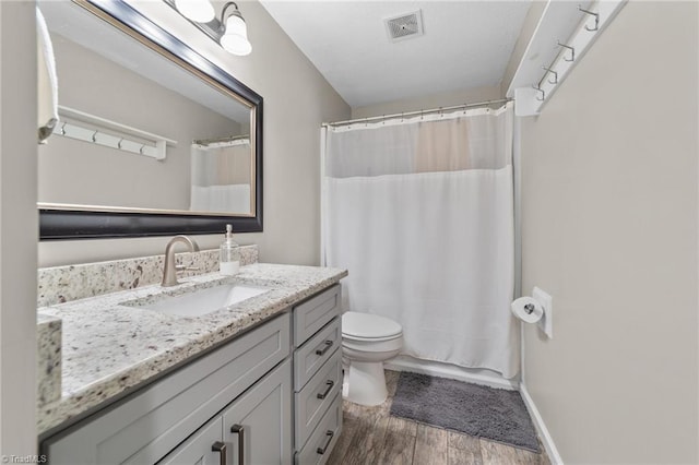 bathroom with visible vents, a shower with shower curtain, toilet, wood finished floors, and vanity