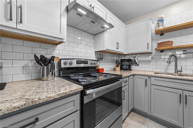 kitchen with stainless steel electric stove, gray cabinets, under cabinet range hood, open shelves, and a sink