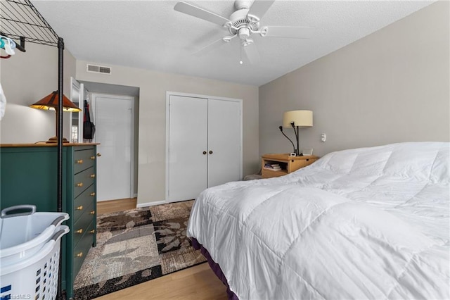 bedroom featuring visible vents, ceiling fan, wood finished floors, a textured ceiling, and a closet