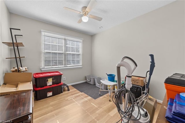 interior space with a textured ceiling, wood finished floors, a ceiling fan, and baseboards