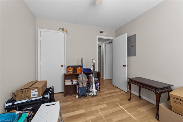 home office with electric panel, visible vents, a textured ceiling, and light wood finished floors