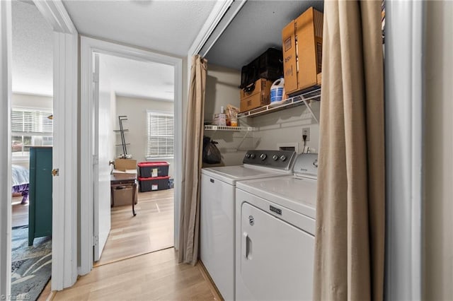 washroom with light wood-style floors, washer and dryer, laundry area, and a textured ceiling