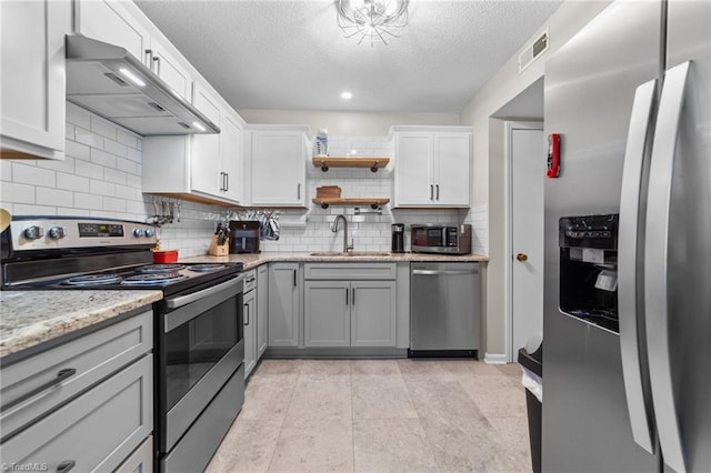 kitchen with open shelves, visible vents, appliances with stainless steel finishes, a sink, and under cabinet range hood