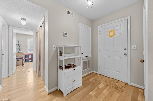 entrance foyer with light wood-type flooring, visible vents, and baseboards