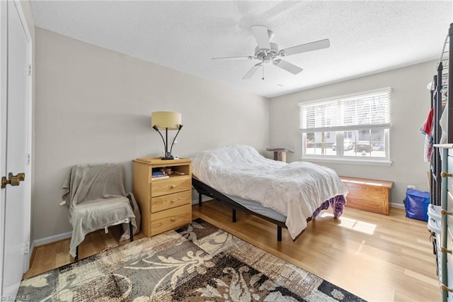 bedroom with a textured ceiling, baseboards, and wood finished floors