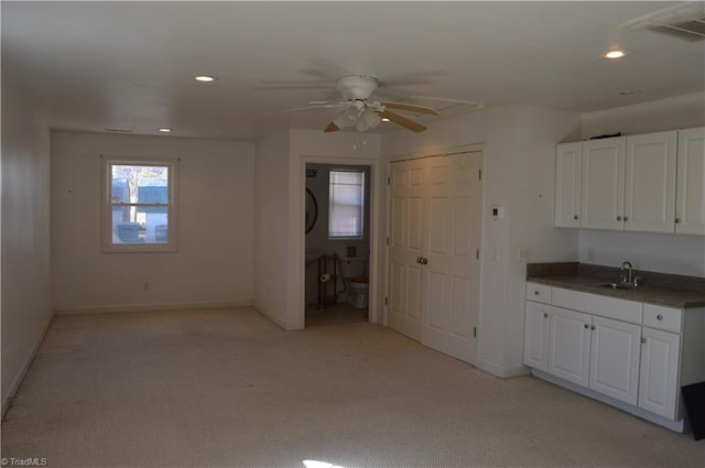 kitchen with light carpet, dark countertops, white cabinetry, a sink, and recessed lighting