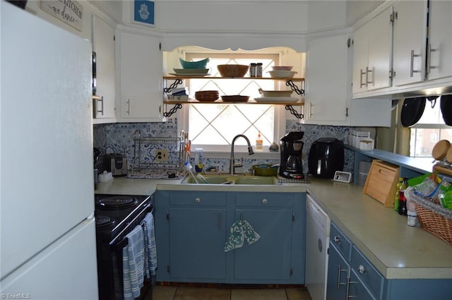 kitchen featuring white appliances, decorative backsplash, light countertops, blue cabinetry, and a sink