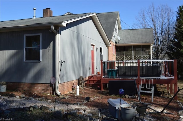 view of side of property featuring a deck, a chimney, and a sunroom