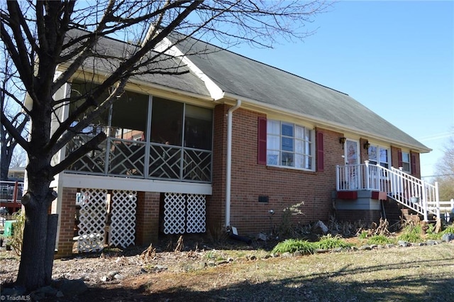 view of side of property featuring brick siding, crawl space, and a sunroom