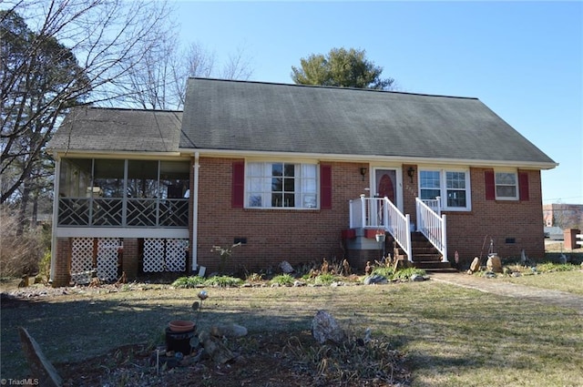 view of front of house with a sunroom, brick siding, and a front lawn