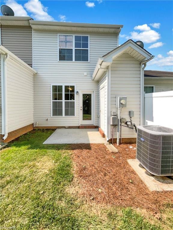 rear view of house with cooling unit, a yard, and a patio area