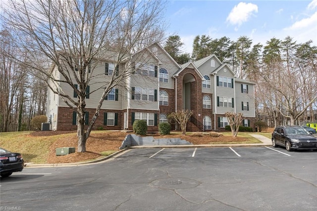 view of property with uncovered parking and central AC unit