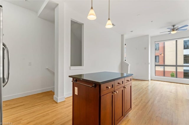 kitchen with light wood-style flooring, refrigerator, dark countertops, baseboards, and decorative light fixtures