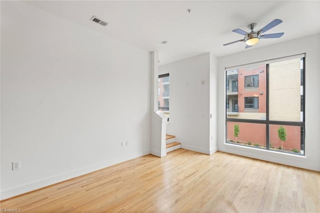 spare room with wood finished floors, baseboards, stairway, and ceiling fan