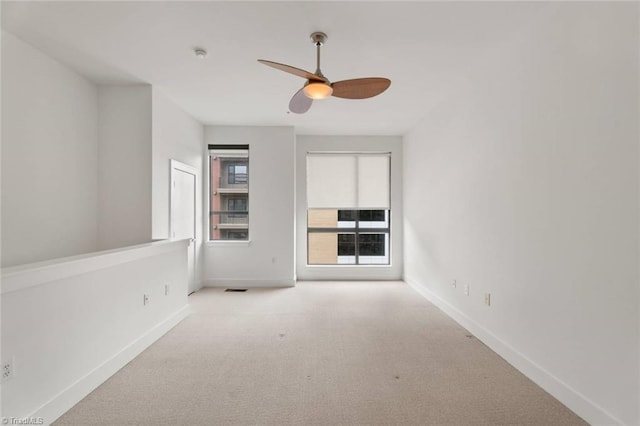 empty room with carpet flooring, baseboards, ceiling fan, and a smoke detector