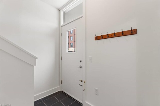 doorway featuring dark tile patterned floors and baseboards
