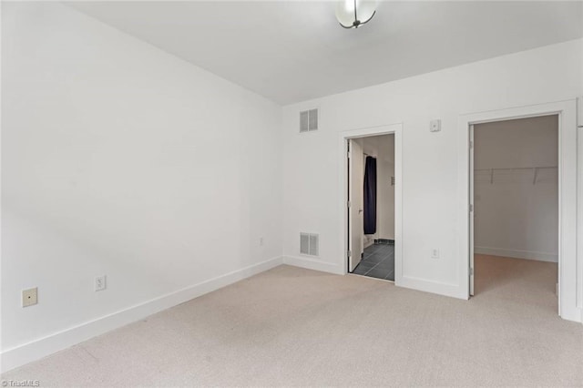unfurnished bedroom featuring carpet, a spacious closet, a closet, and baseboards