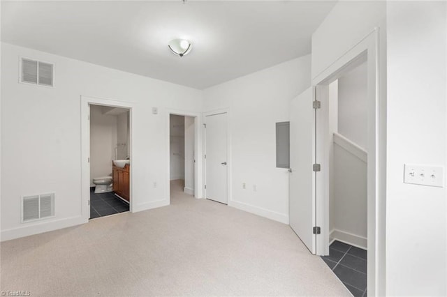 unfurnished bedroom with carpet flooring, baseboards, connected bathroom, and tile patterned floors