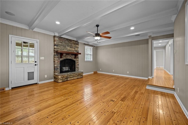 unfurnished living room with a ceiling fan, baseboards, a fireplace, beamed ceiling, and light wood-type flooring