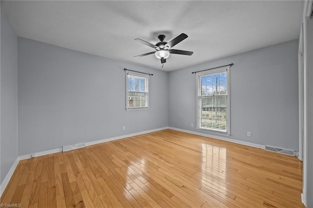 unfurnished room featuring plenty of natural light, light wood-style flooring, and baseboards