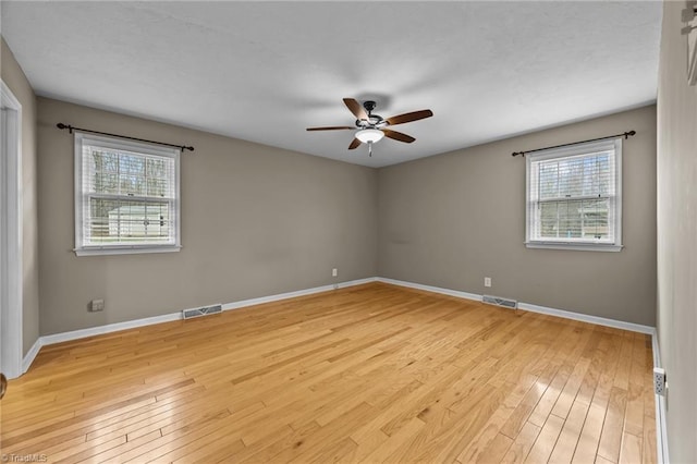 spare room with a wealth of natural light, visible vents, and light wood-type flooring