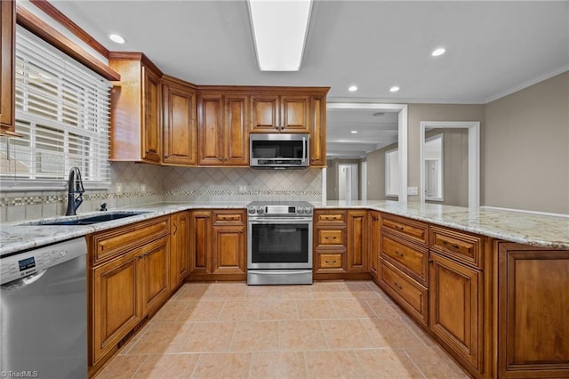 kitchen with brown cabinets, a peninsula, stainless steel appliances, and a sink