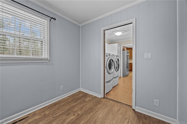 clothes washing area with visible vents, crown molding, washing machine and dryer, laundry area, and wood finished floors