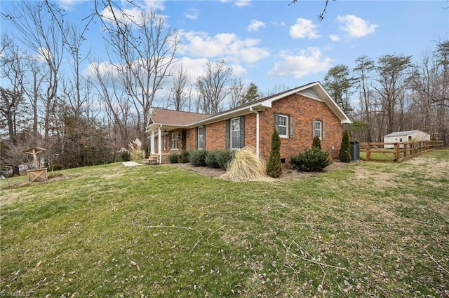 view of property exterior with a yard, fence, and brick siding