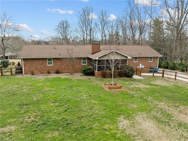 back of property featuring a lawn, brick siding, a fenced backyard, and a chimney