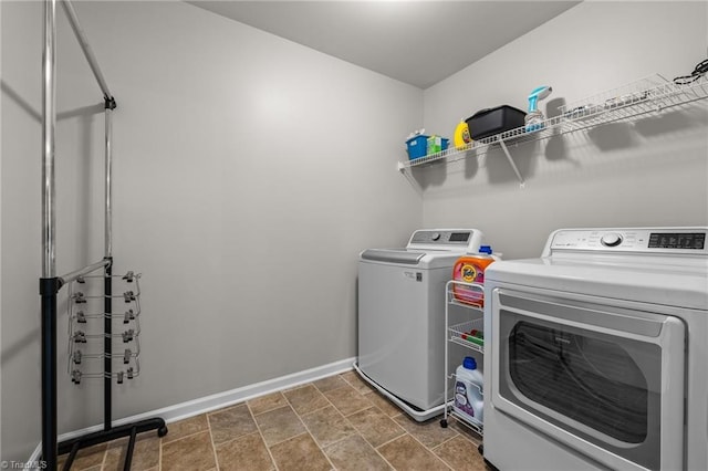 washroom with stone finish floor, laundry area, baseboards, and independent washer and dryer