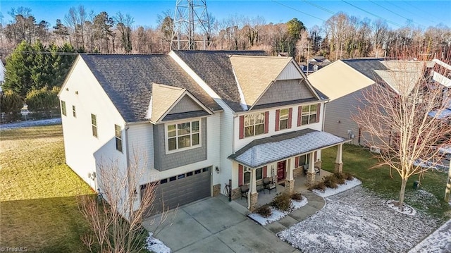 view of front of property featuring driveway, covered porch, a garage, and a front lawn