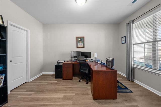 office space with light wood-type flooring, visible vents, and baseboards