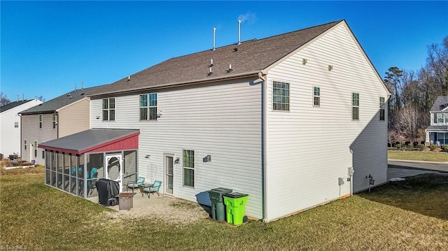 back of property with a sunroom, a patio area, and a lawn